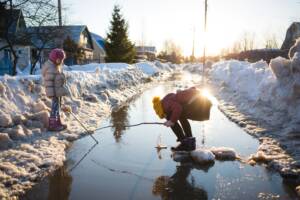 Children Play In Puddle On Street In Early Spring